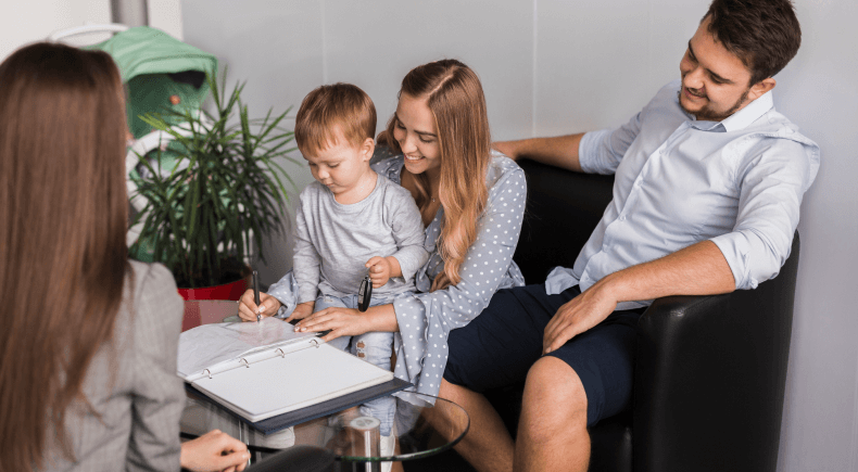 FAMILIA SENTADA MIENTRAS LA MUJER FIRMA ALGO